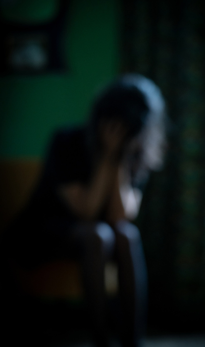Out of focus shot of person covering face with hands in dark room