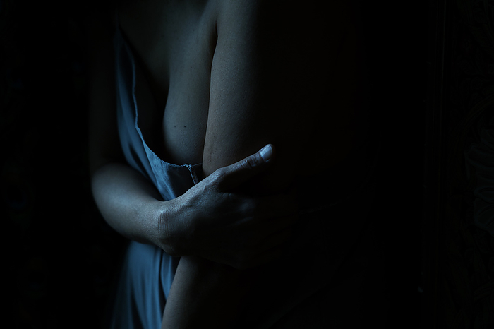 Dark image of woman's arm holding her torso
