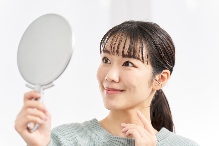 Japanese woman checking her appearance in the mirror (People)