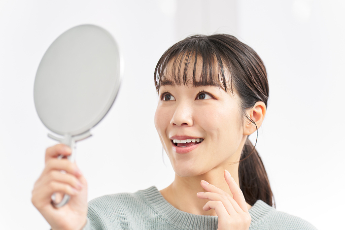 Japanese woman checking her teeth in a mirror.