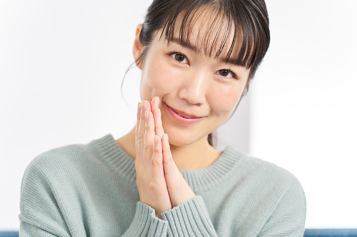 A Japanese woman with her hands together making a request (People)