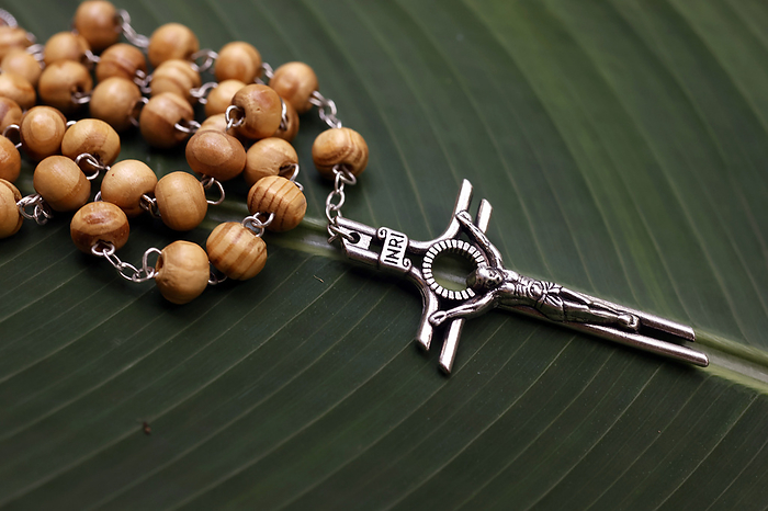 Rosary or prayer beads on a green leave. Jesus on the cross. Crucifix. Rosary  prayer beads  on a green leaf, and Jesus on the Cross  Crucifix , Cambodia, Indochina, Southeast Asia, Asia, by Godong