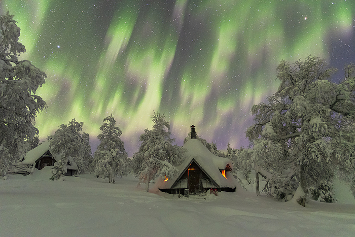 Winter view of a typical wooden hut lit by the fire in the frozen wood during a northern lights storm, Finnish Lapland, Finland, Scandinavia, Europe Winter view of a typical wooden hut lit by the fire in the frozen wood during a Northern Lights  Aurora Borealis  storm, Finnish Lapland, Finland, Europe, by Paolo Graziosi