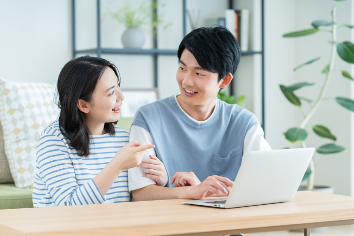 A young Japanese couple on a computer in the living room (People)