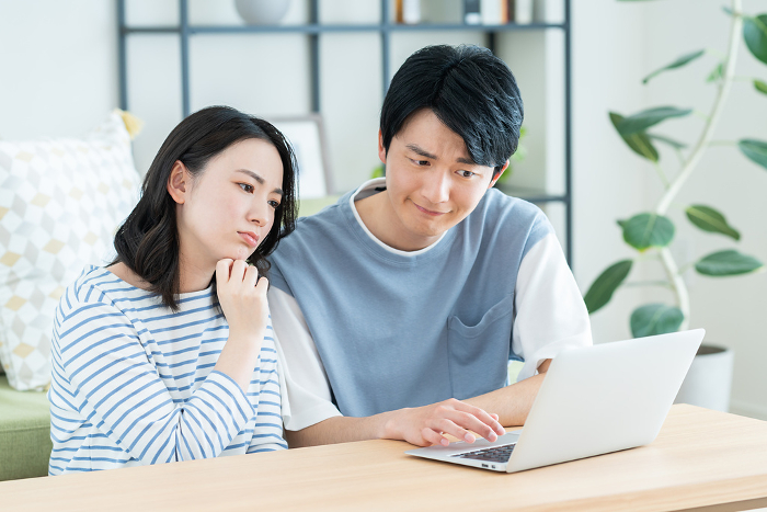 A young Japanese couple on a computer in the living room (People)