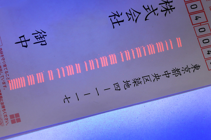 Transparent barcodes printed on New Year s cards are illuminated with a black light. Company names have been eliminated.
