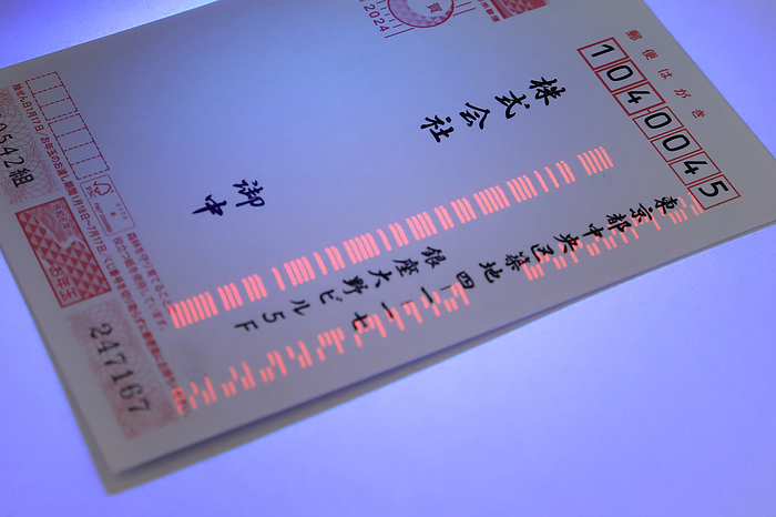 Transparent barcodes printed on New Year s cards are illuminated with a black light. Company names have been eliminated.