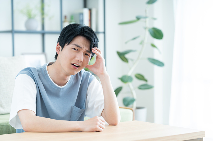 Young Japanese man distressed in his living room.