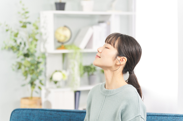 Japanese woman closing her eyes in the living room.