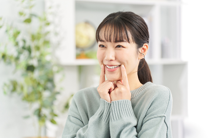 A Japanese woman practicing her smile in the living room.
