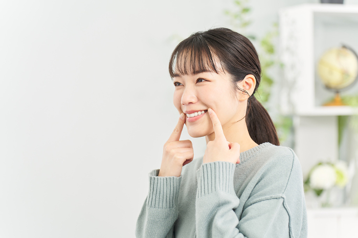 A Japanese woman practicing her smile in the living room.