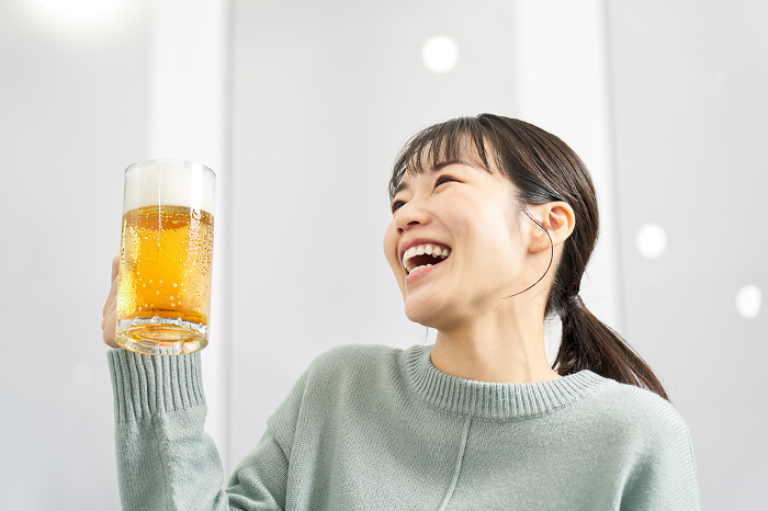Japanese woman drinking beer from a mug at home (People)