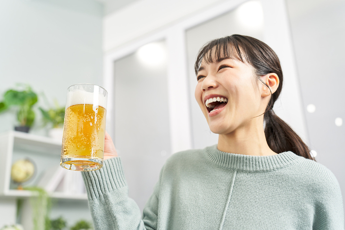 Japanese woman drinking beer from a mug at home (People)
