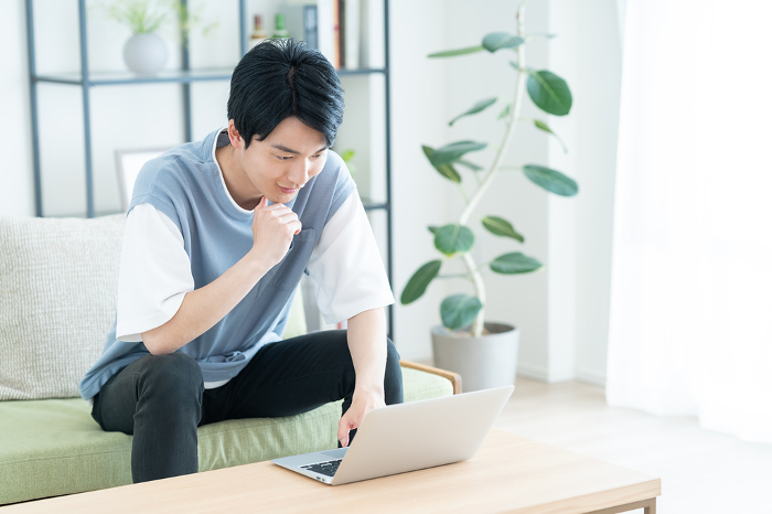Young Japanese man on computer in living room (People)