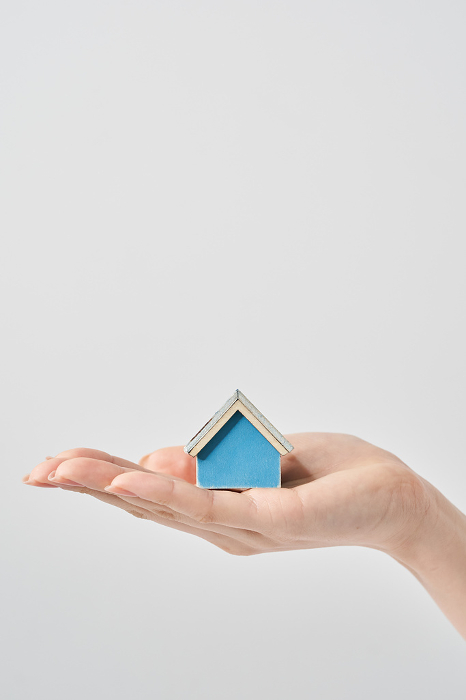 Model of a house placed in the palm of a woman's hand