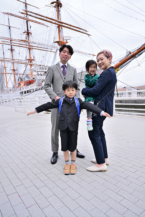 A family poses for a photo with the Nippon Maru in the background.
