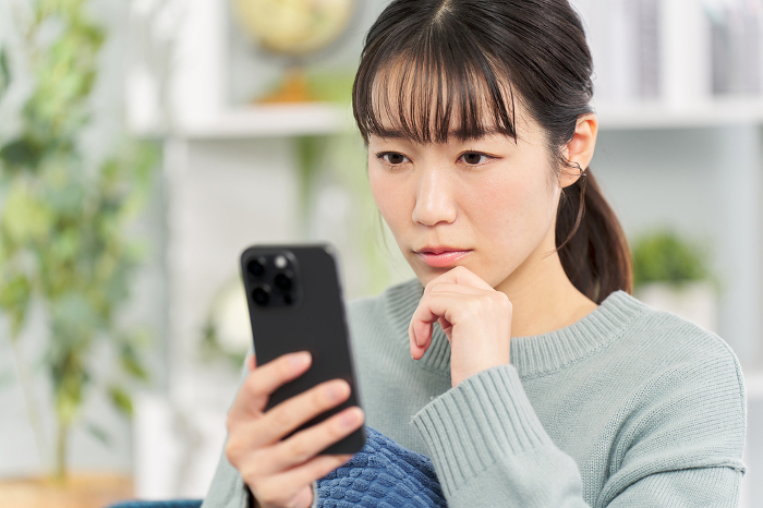 Japanese woman looking at her smartphone with a serious expression on her face.