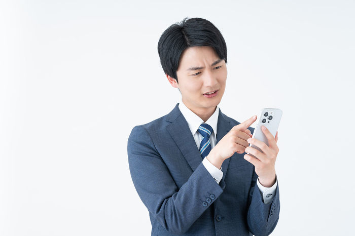 Young Japanese businessman troubled by his phone (People)