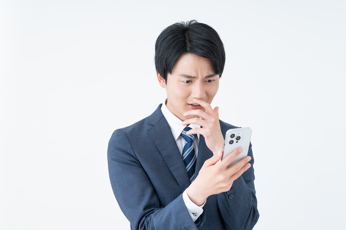 Young Japanese businessman surprised by his phone (People)