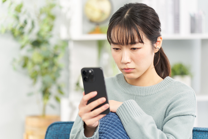 Japanese woman looking at her smartphone with a serious expression on her face.