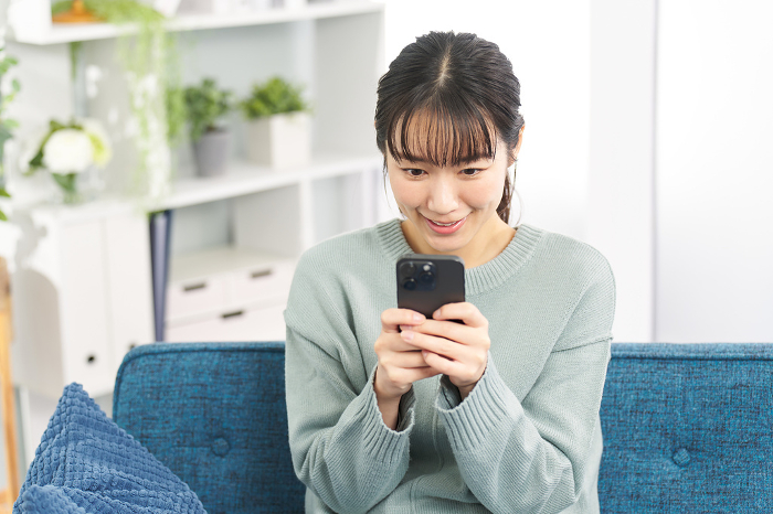 Japanese woman playing a game on a smartphone (People)