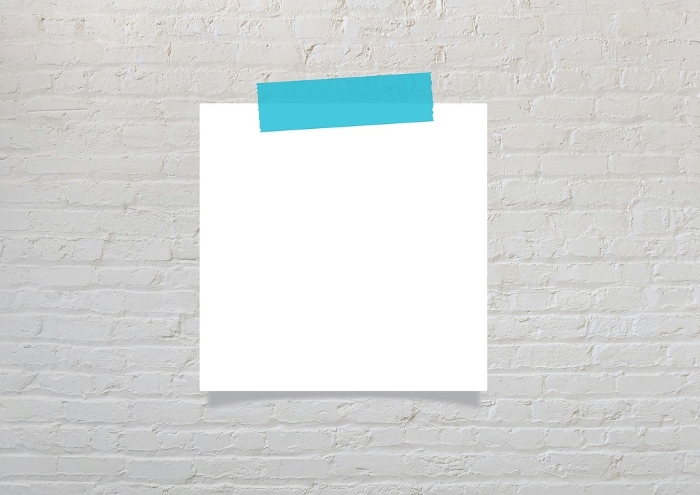 Light blue masking tape and blank notepaper on gray brick wall
