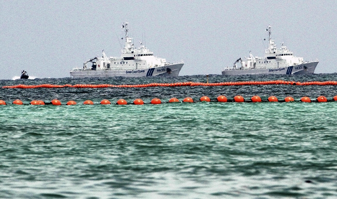 Construction of the new U.S. military base at Henoko Buoys to be set up for undersea survey A Japan Coast Guard patrol boat on alert around the float  1:03 p.m., Aug. 16, 2014, in Nago City, Okinawa Prefecture . On the morning of August 16, a standoff continued in the Henoko coastal area of Nago City, Okinawa Prefecture, over the relocation plan for the U.S. Futenma Air Station  Ginowan City  in Okinawa Prefecture, with about 50 Coast Guard rubber boats and other vessels on alert for the upcoming undersea drilling survey. On the 15th, buoys were installed along the coastline to prevent intruders from entering the site of the borehole survey. The Okinawa Defense Bureau is expected to place a drilling barge inside the buoys on the 16th. Opposition groups protested in front of the gate of the U.S. military s Camp Schwab, which faces the site waters.
