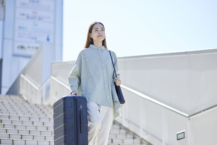 Female inbound foreign traveler descending stairs with suitcase