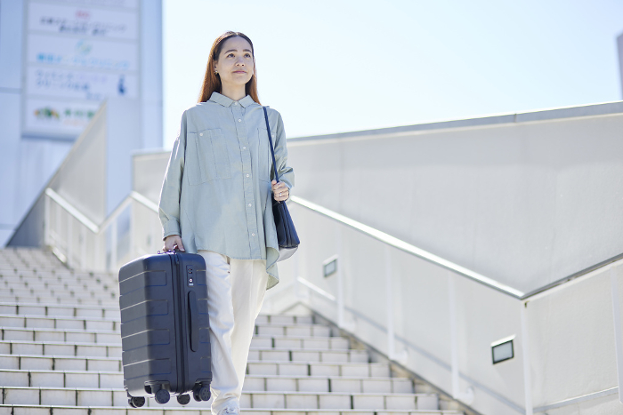 Female inbound foreign traveler descending stairs with suitcase