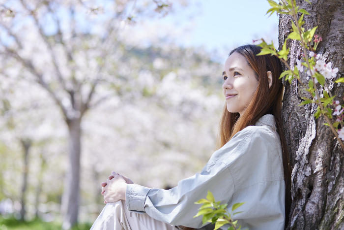 Foreign tourist woman relaxing under a cherry tree