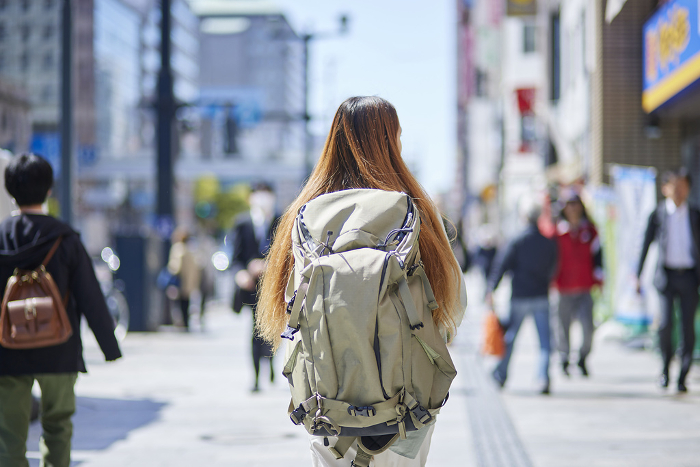 A female foreign tourist walking in the city with a backpack on her back