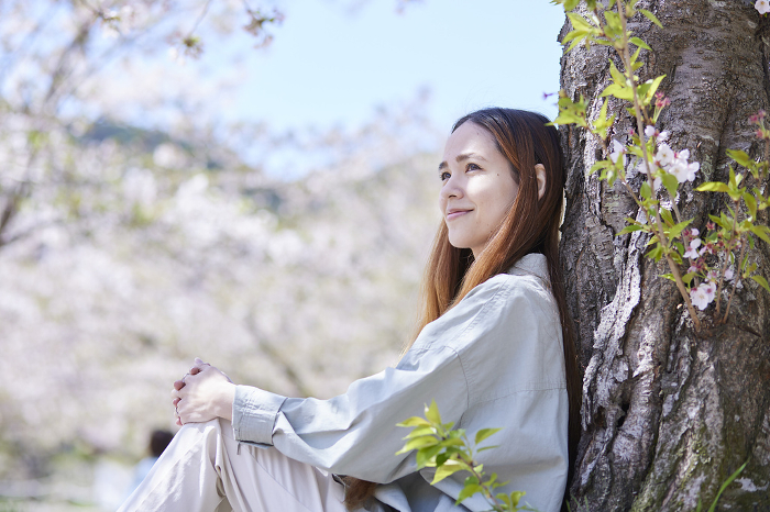 Foreign tourist woman relaxing under a cherry tree