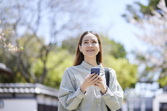 Inbound tourist woman with smartphone at a tourist attraction in spring