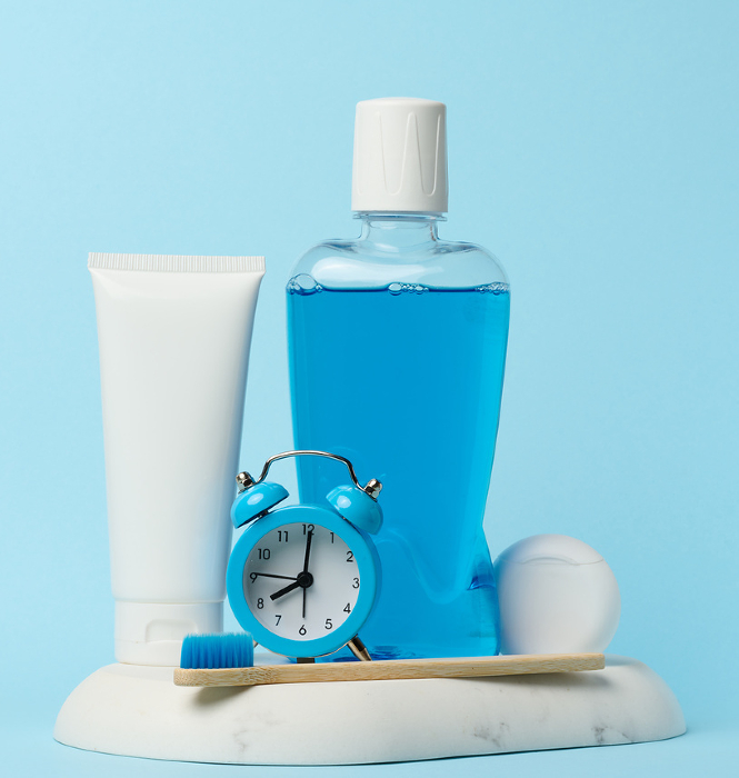 Mouthwash and toothpaste tube, alarm clock on blue background, oral hygiene Mouthwash and toothpaste tube, alarm clock on blue background, oral hygiene