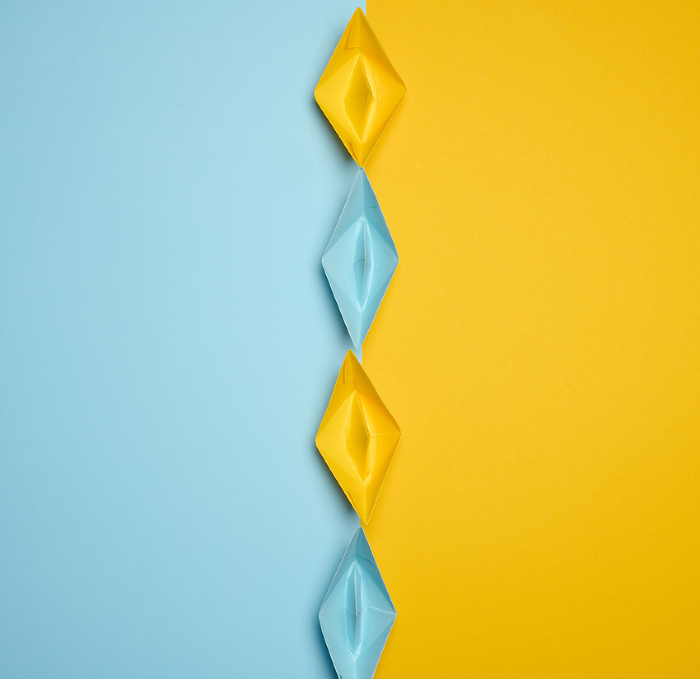 Paper boats on a yellow background, top view, representing the concept of unity and achieving common goals. Top view Paper boats on a yellow background, top view, representing the concept of unity and achieving common goals. Top view