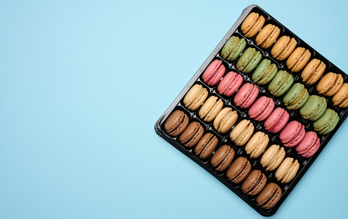 Multi colored macarons on a blue background in a plastic box, top view. Copy space Multi colored macarons on a blue background in a plastic box, top view. Copy space