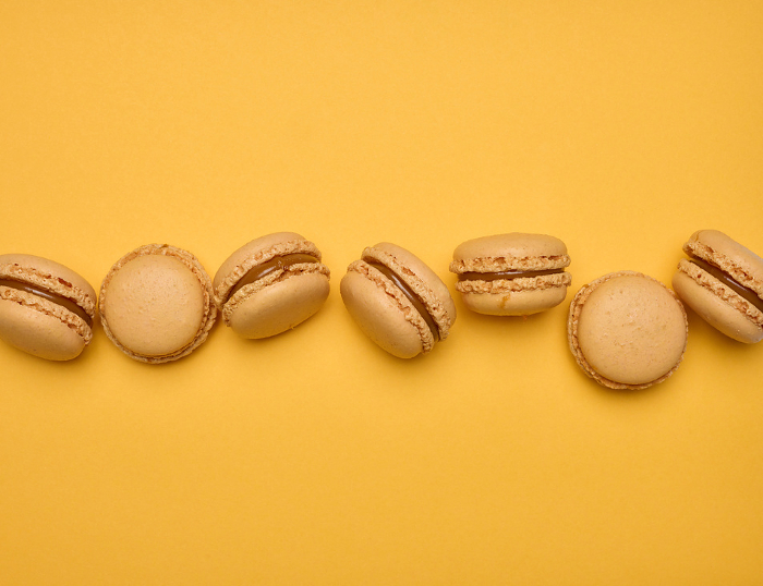 Chocolate macarons on a yellow background, dessert. Top view Chocolate macarons on a yellow background, dessert. Top view