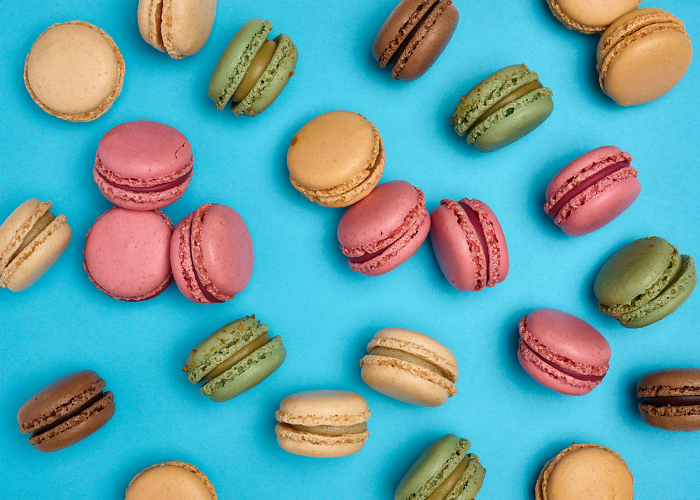 Multicolored macarons on a blue background, top view, dessert Multicolored macarons on a blue background, top view, dessert