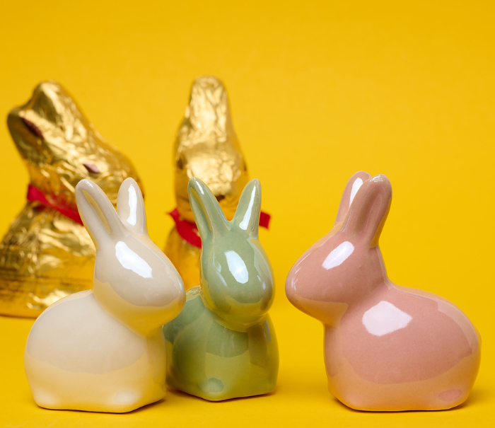Ceramic decorative bunnies on a yellow background, festive Easter background Ceramic decorative bunnies on a yellow background, festive Easter background