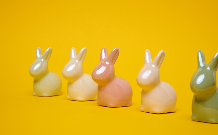 Ceramic decorative bunnies on a yellow background, festive Easter background Ceramic decorative bunnies on a yellow background, festive Easter background