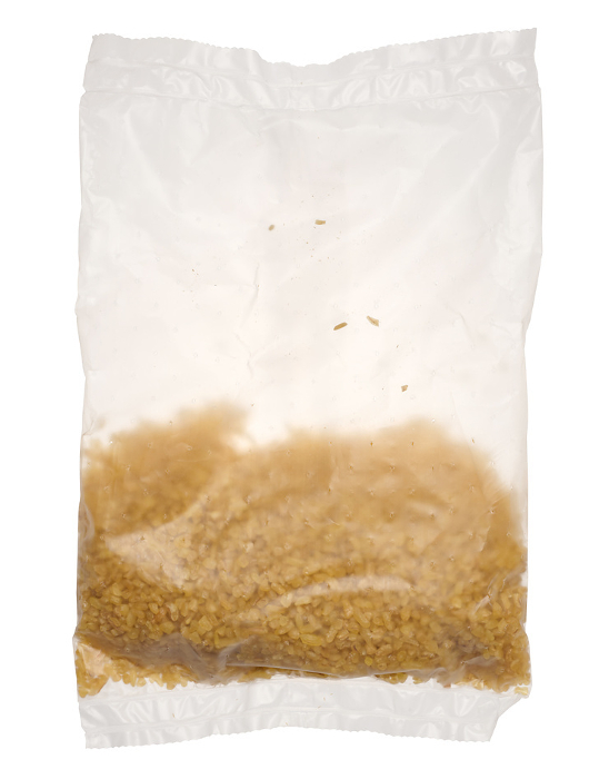Raw bulgur grains in a cellophane transparent bag on an isolated background Raw bulgur grains in a cellophane transparent bag on an isolated background