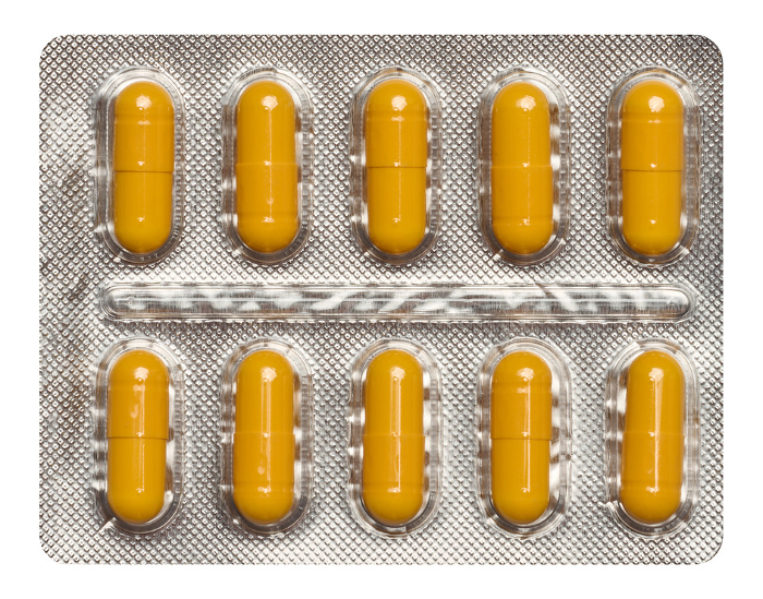 Oval yellow tablets in white plastic packaging, top view Oval yellow tablets in white plastic packaging, top view