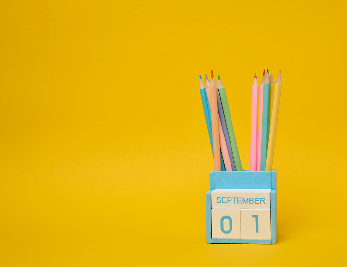 Multi colored pencils and the date the first of September on the calendar. Yellow background Multi colored pencils and the date the first of September on the calendar. Yellow background