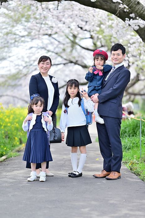 A family standing on the promenade of a park where cherry blossoms are in bloom