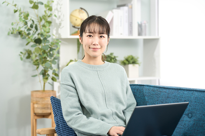 Japanese woman operating a laptop computer in the living room (People)