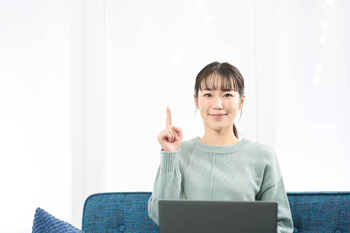 Japanese woman pointing while operating a laptop computer (People)