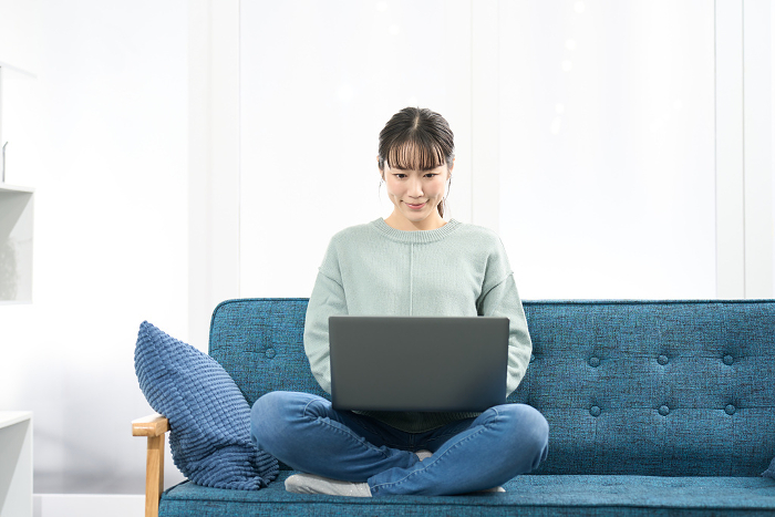Japanese woman operating a laptop computer in the living room (People)