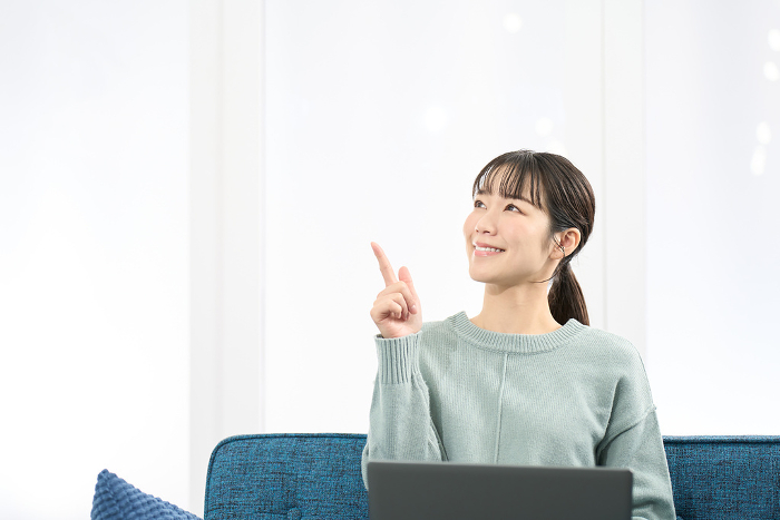 Japanese woman pointing while operating a laptop computer (People)
