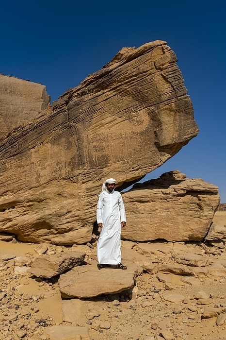 Saudi Arabia Man pointing at rock carvings, Unesco site Bir Hima Rock Petroglyphs and Inscriptions, Najran, Kingdom of Saudi Arabia