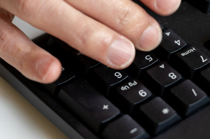 Fingertips hitting the number keys on the keyboard